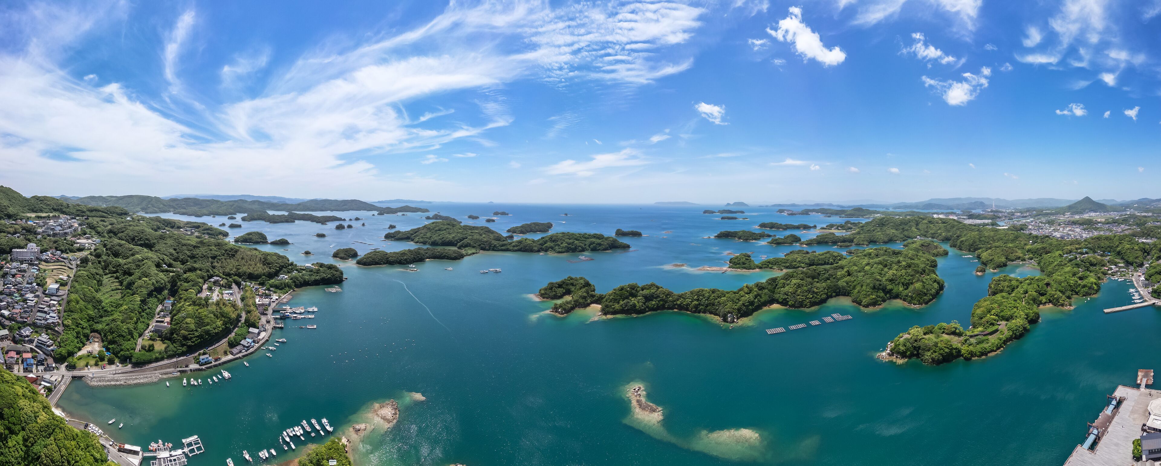 A coastal town with a marina, surrounded by lush green islands and clear blue waters.