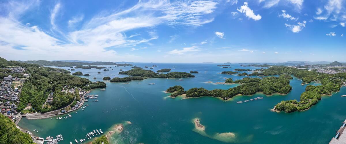 A coastal town with a marina, surrounded by lush green islands and clear blue waters.