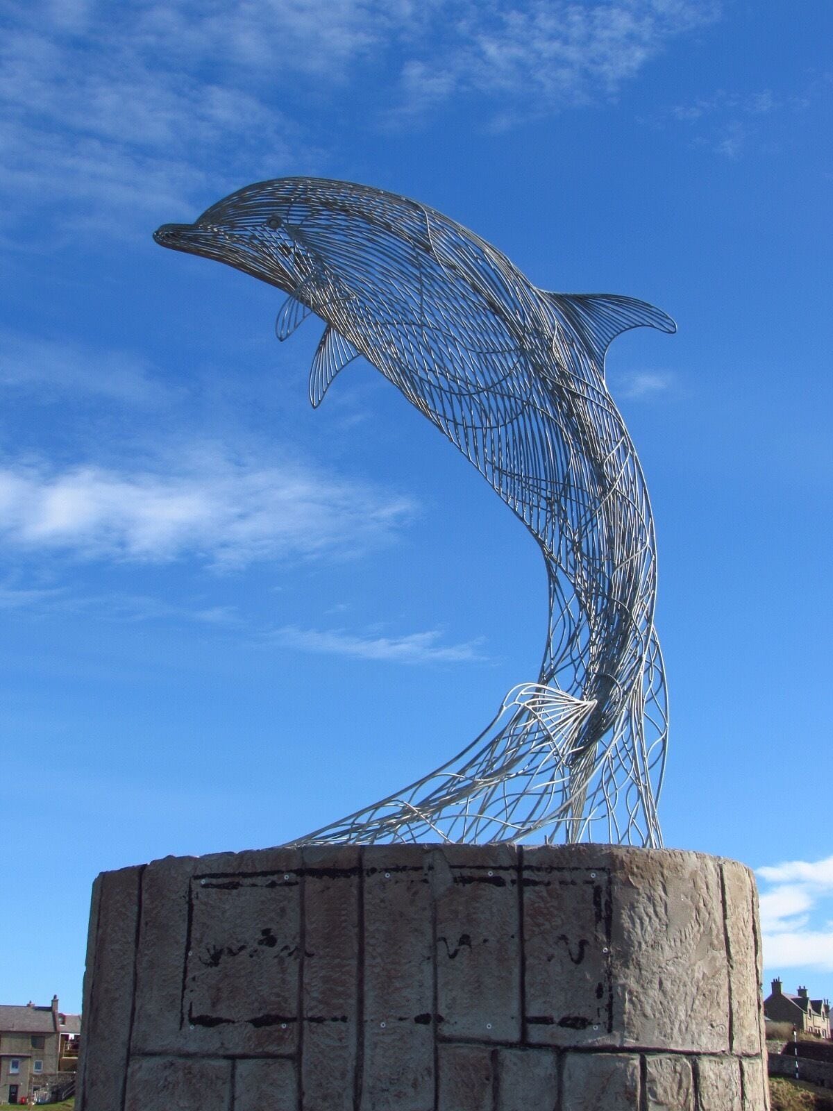 Eight years ago, Carn Standing met a young woman on the Doonie beside the remains of the gable end at Portsoy Harbour. She was disabled and very ill, but had been camping there for a number of weeks. He asked her why she was there, to which she replied that she’d been waiting for the dolphins. Carn was inspired by her spirit and determination, and since this encounter, seeing dolphins has always reminded him of this brave woman. This prompted him to create a life size dolphin sculpture out of mild steel and galvanized to protect it from rust, for the 2014 'Scottish Traditional Boat Festival' in Portsoy.  