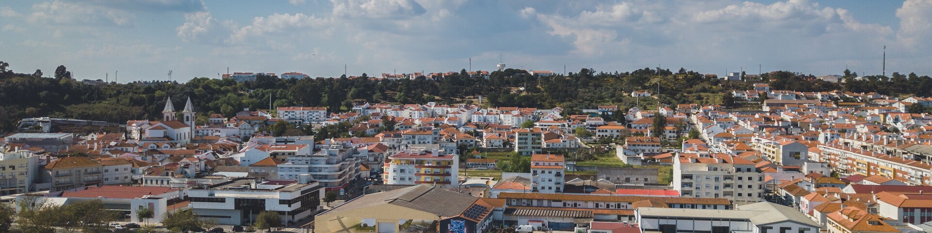 Una plaza de toros rodeada de una zona residencial con casas de techo rojo.
