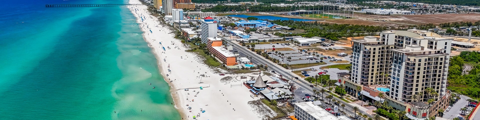 Eine Küstenstadt mit einem langen Strand, klarem türkisblauem Wasser und Hochhäusern.