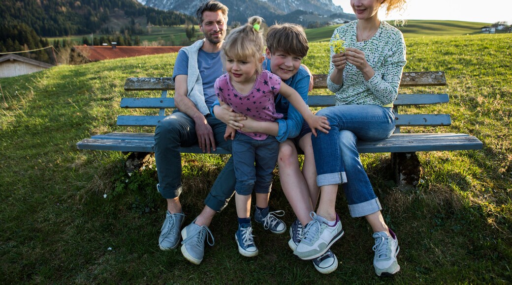 Austria, Tyrol, Walchsee, happy family resting on a bench in the mountains