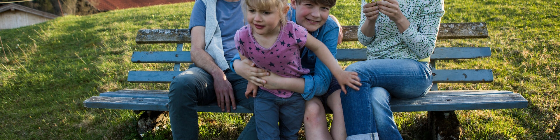 Austria, Tyrol, Walchsee, happy family resting on a bench in the mountains