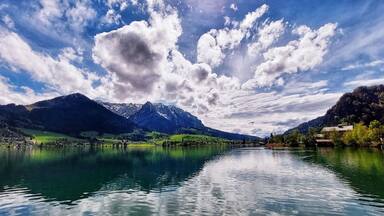 A calm lake surrounded by mountains and a clear sky.