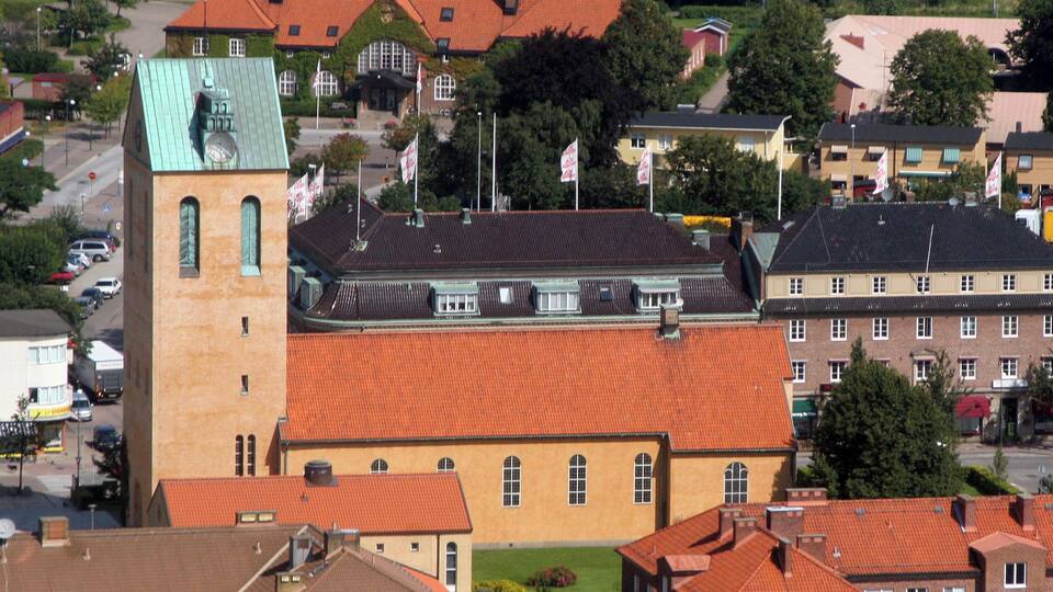 A town with a prominent church featuring a tall tower and a large building with a red roof.