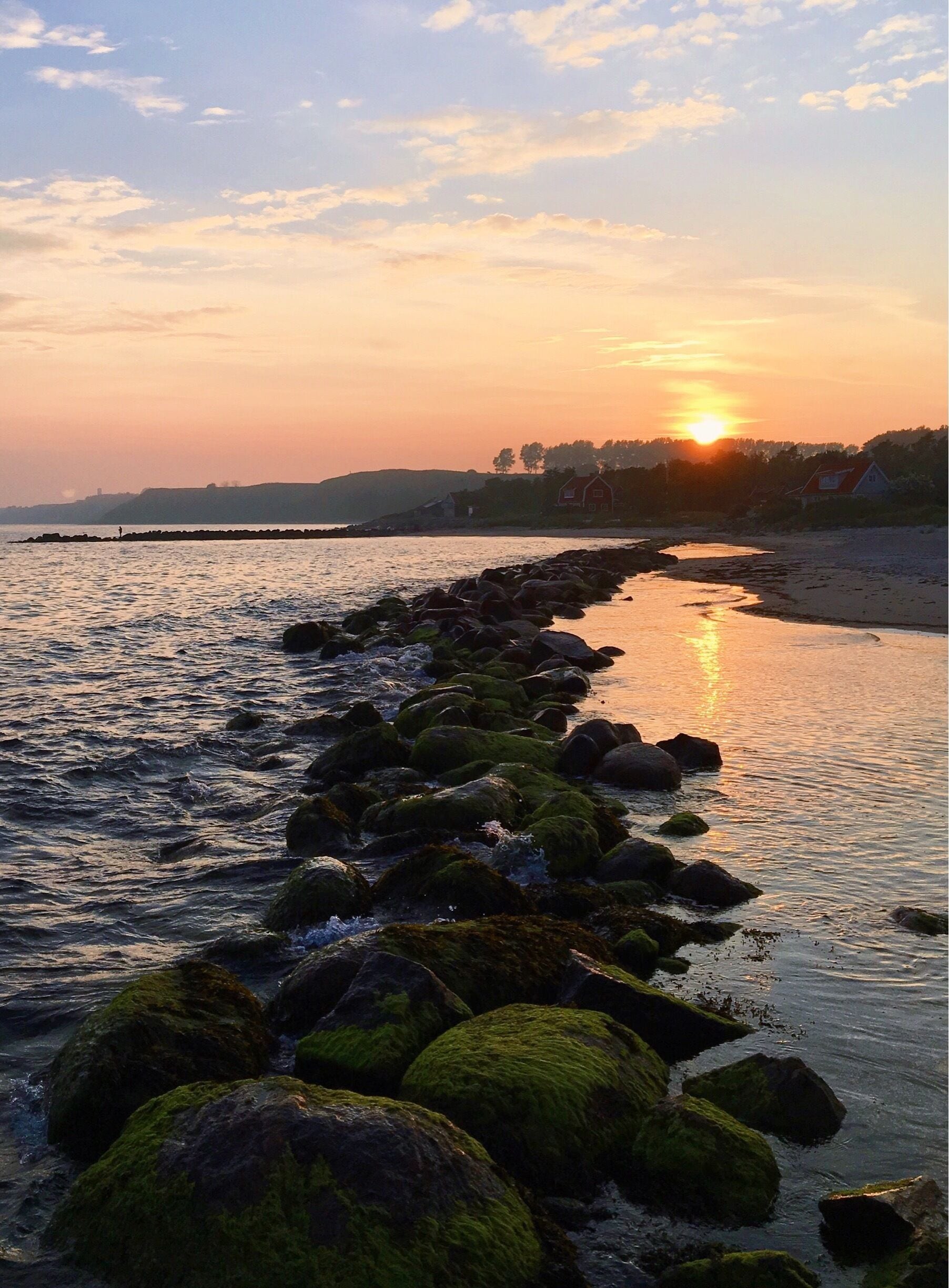 A rocky shoreline with a sunset in the background.