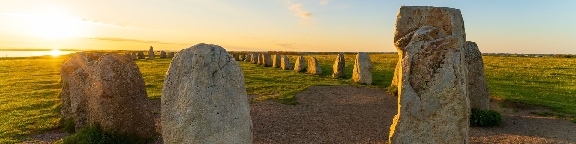 Stonehenge erguido en un campo con un atardecer de fondo.