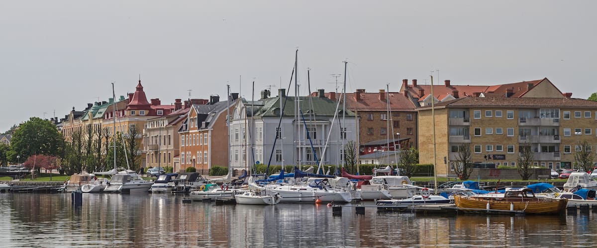 A marina with various boats docked, surrounded by colorful buildings with distinct architectural styles.