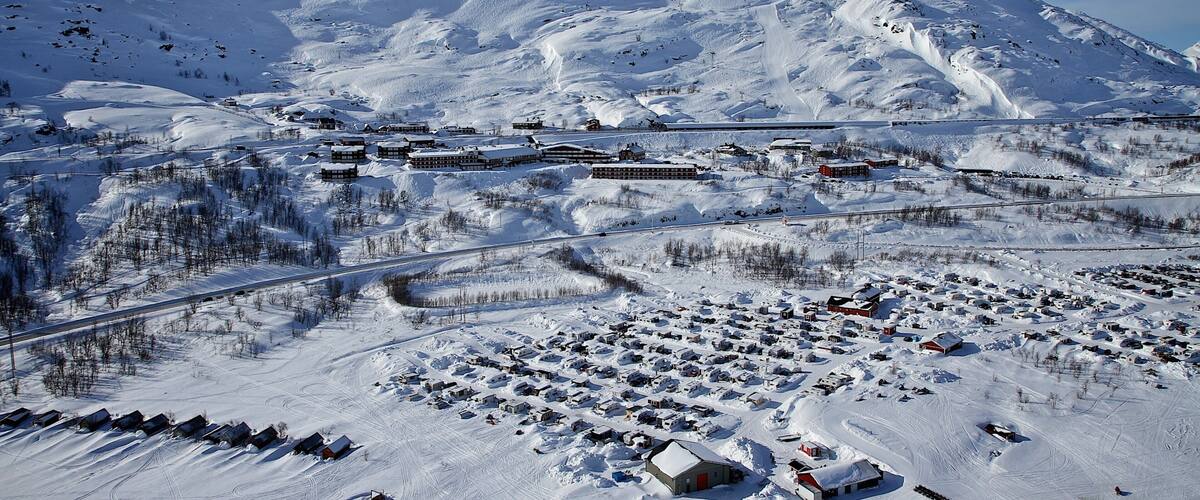 A snow-covered mountain with a ski resort and a small town in the foreground.