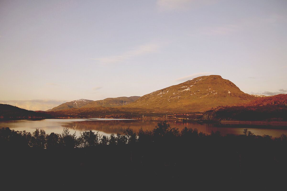 Una montaña con un lago en primer plano y un cielo despejado.