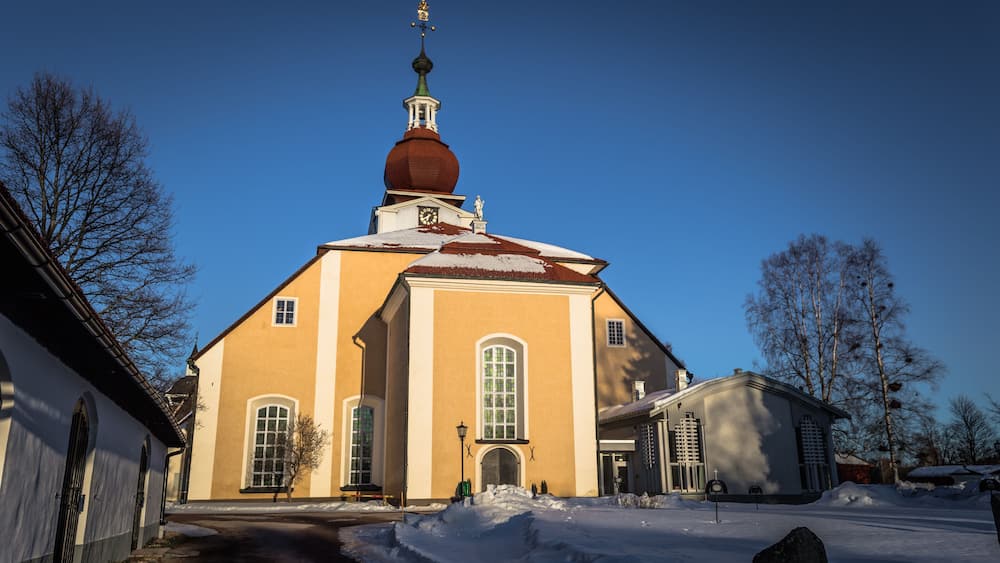 Eine Kirche mit einer roten Kuppel und einem Glockenturm, umgeben von Schnee.