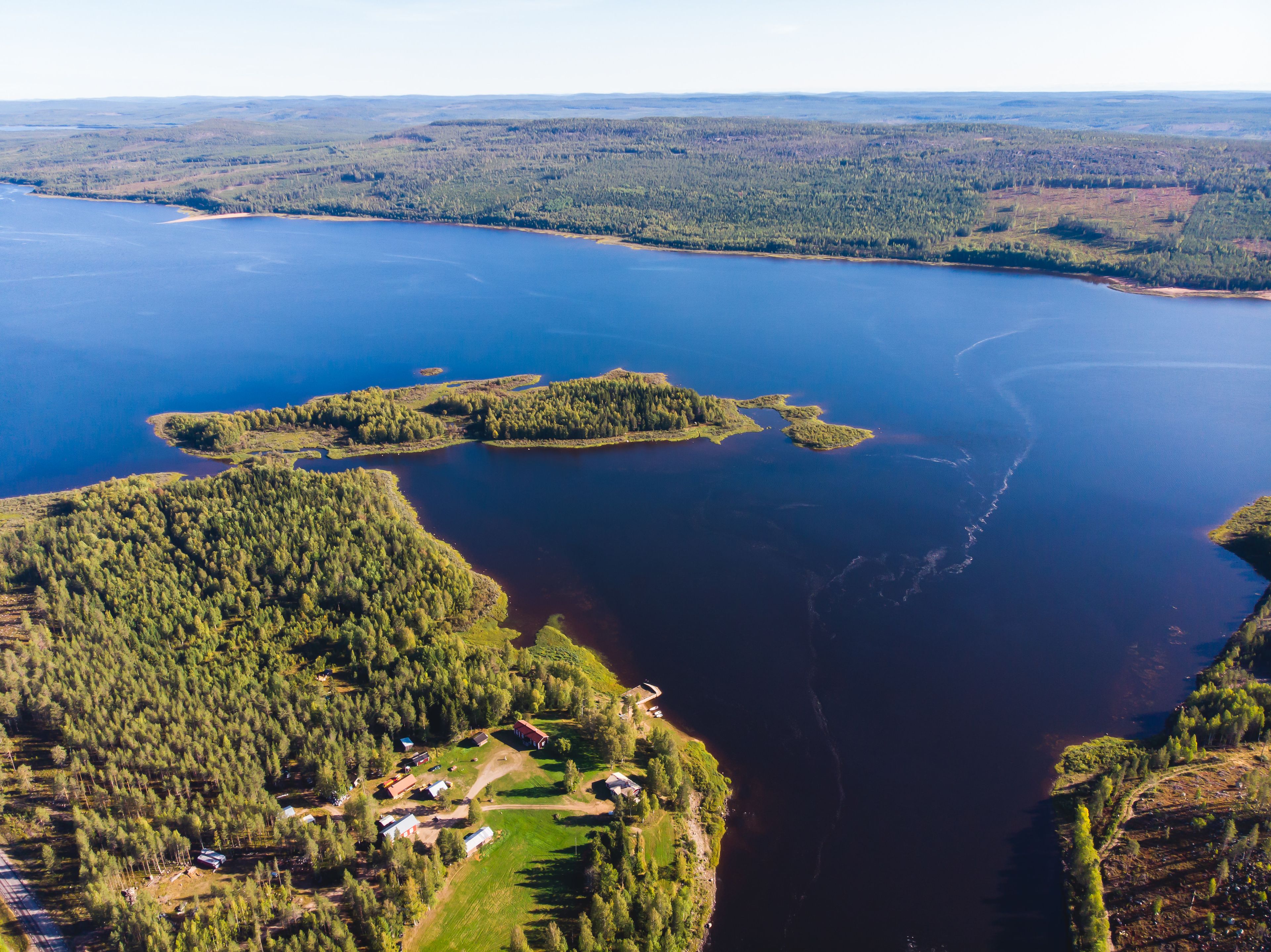 An aerial view of a lake surrounded by dense forests and small settlements.