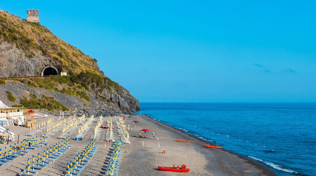 A beach with rows of beach chairs, a red boat, and a castle on a hill.
