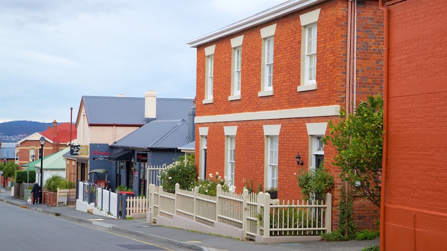 A street lined with red brick buildings, a white picket fence, and a sign for 'The Circus Dragonfly'.