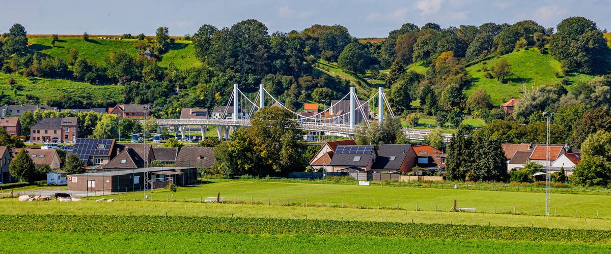 A rural landscape with a bridge, houses, and green fields.