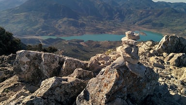 Paisagem montanhosa com um lago azul-turquesa e terreno rochoso.