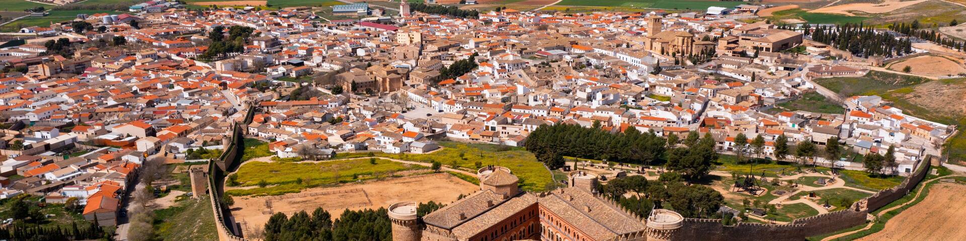 A medieval castle surrounded by a walled town with red-roofed buildings.
