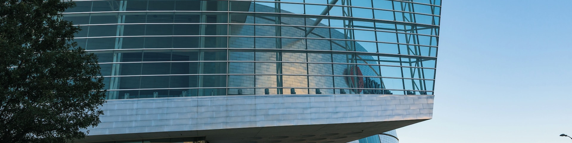 Um edifício moderno de vidro com um design curvo e singular, e um beirado branco.
