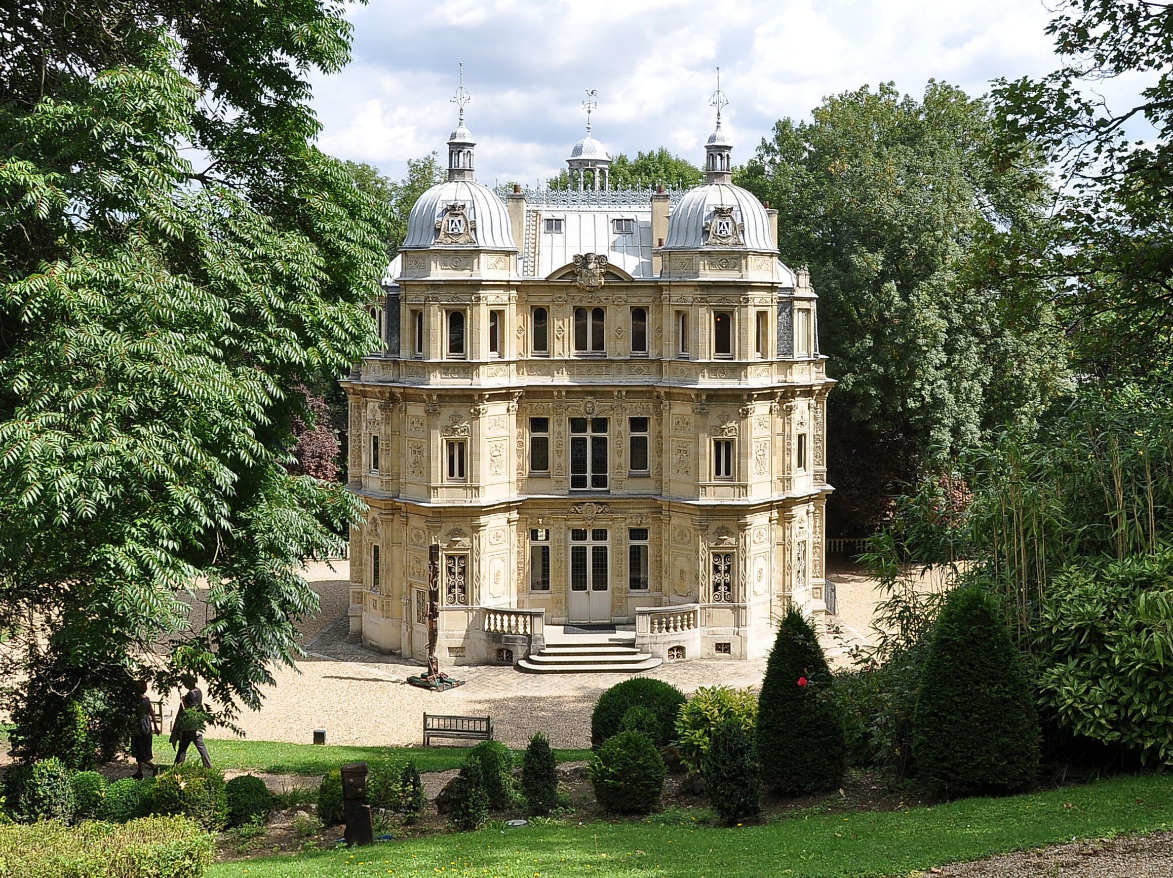 A large, ornate building with domed roofs surrounded by lush greenery.