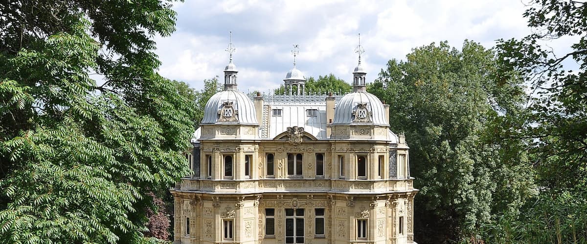 A large, ornate building with domed roofs surrounded by lush greenery.