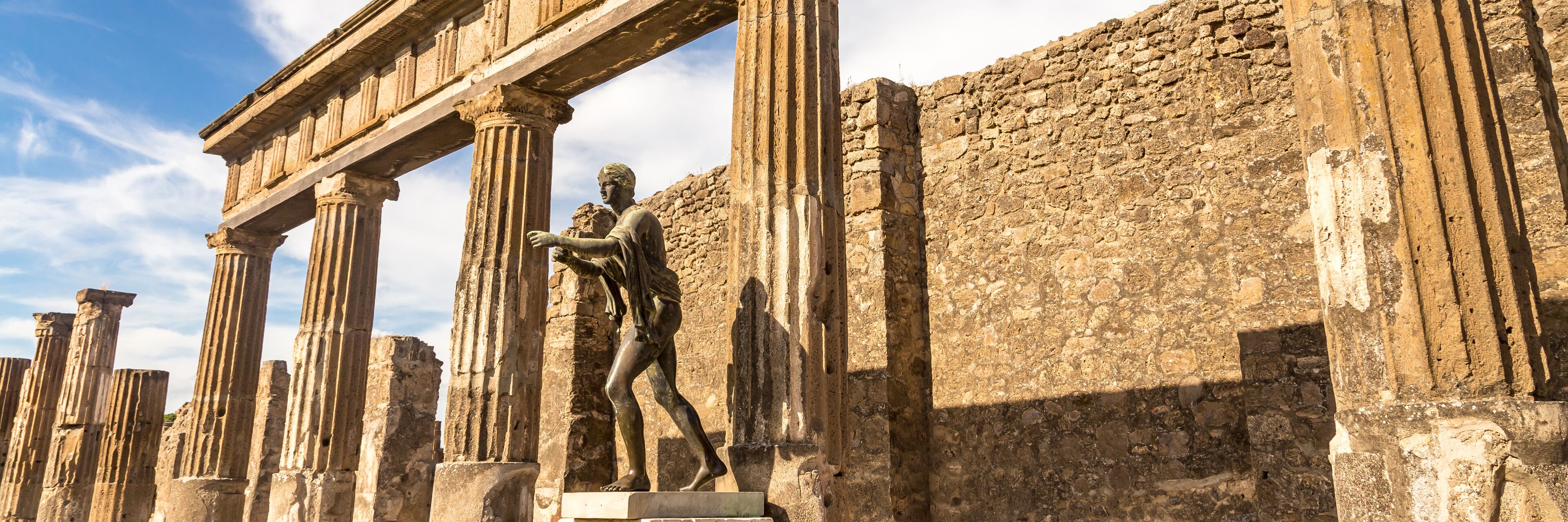 Ancient ruins with columns and a statue.