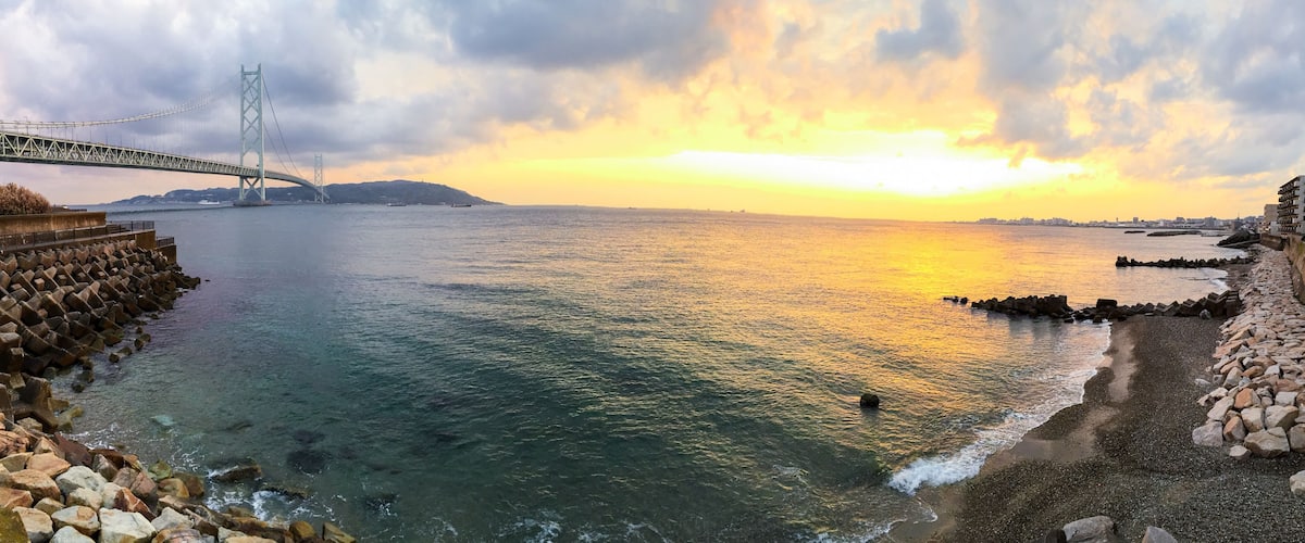 Panoramic sunset view of the sea ,the Akashi-Kaikyo Bridge links the city of Kobe on the Japanese mainland of Honshu to Iwaya on Awaji Island in Japan.
