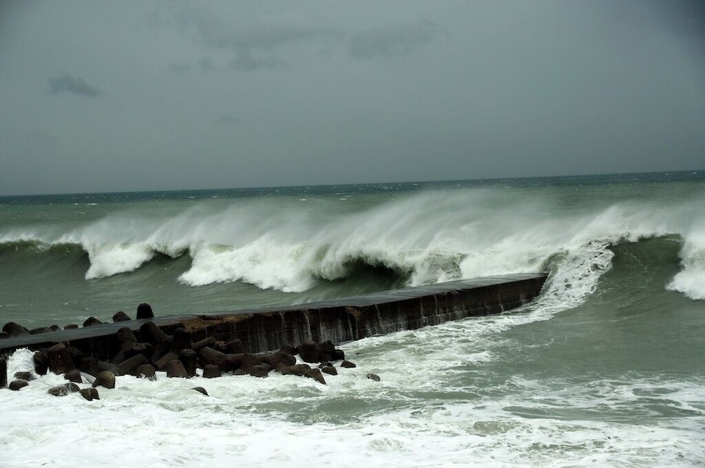 Mar tormentosa con olas rompiendo contra un muro de hormigón.