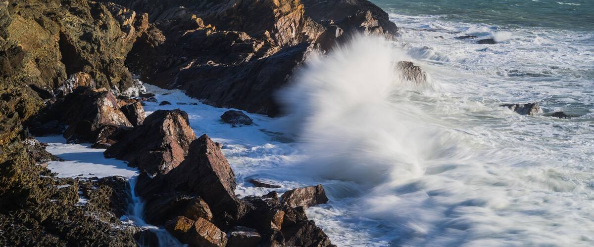 A rocky coastline with a white building on a cliff overlooking the sea.