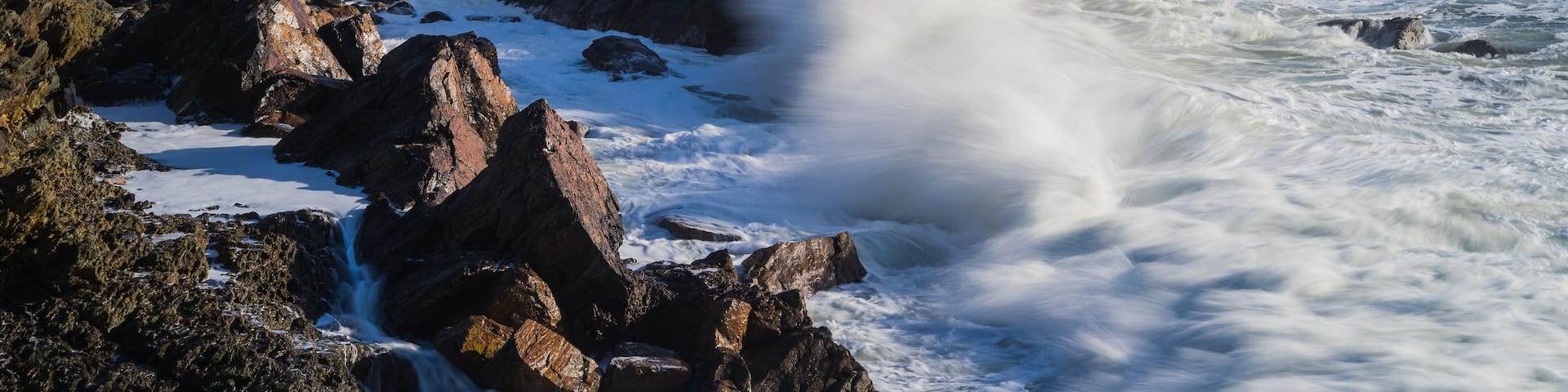 A rocky coastline with a white building on a cliff overlooking the sea.