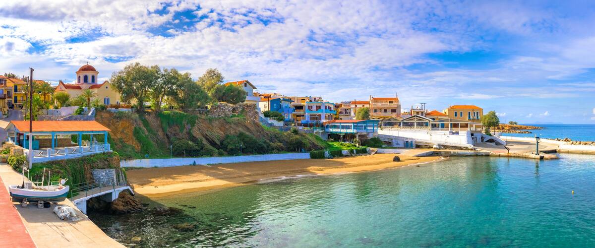 A coastal town with colorful buildings, a beach, and a clear blue sea.