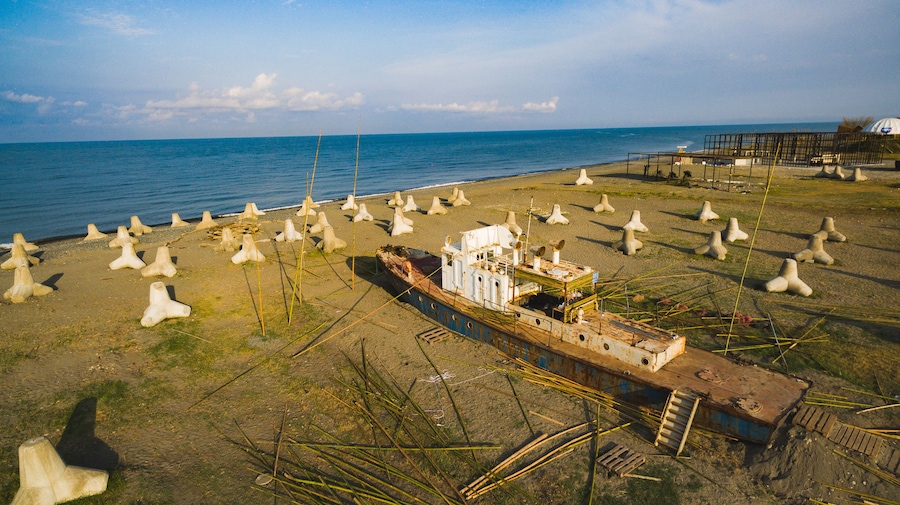 Un barco hundido en la playa, rodeado de numerosas estructuras de hormigón.