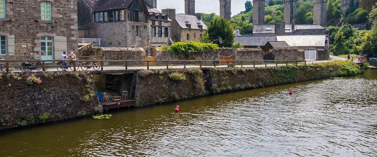 A stone bridge with arches, a river, and historic buildings.