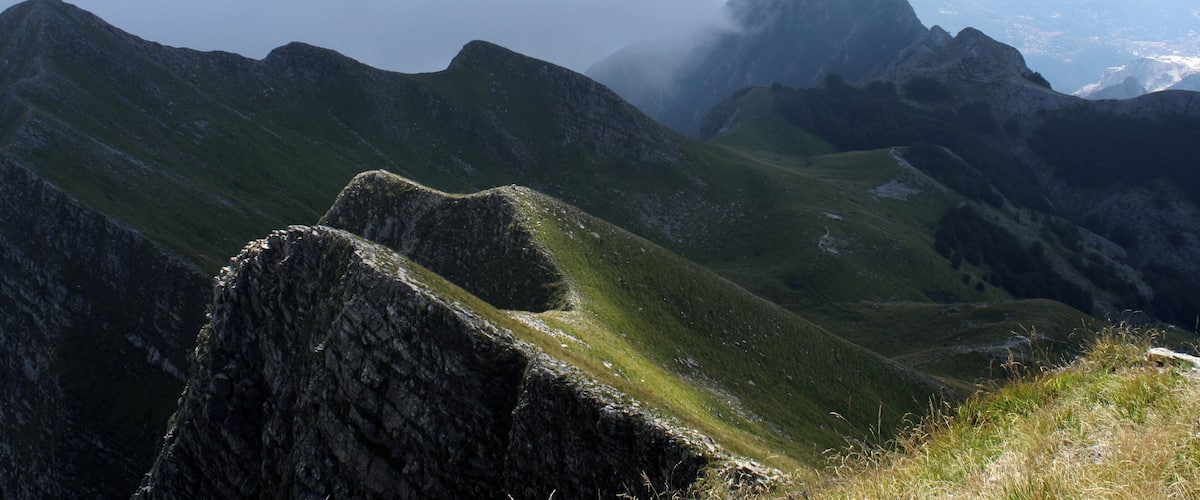 A mountainous landscape with rocky outcrops and grassy slopes.