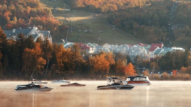 A lakeside town with autumn foliage, boats, and a hilltop church.