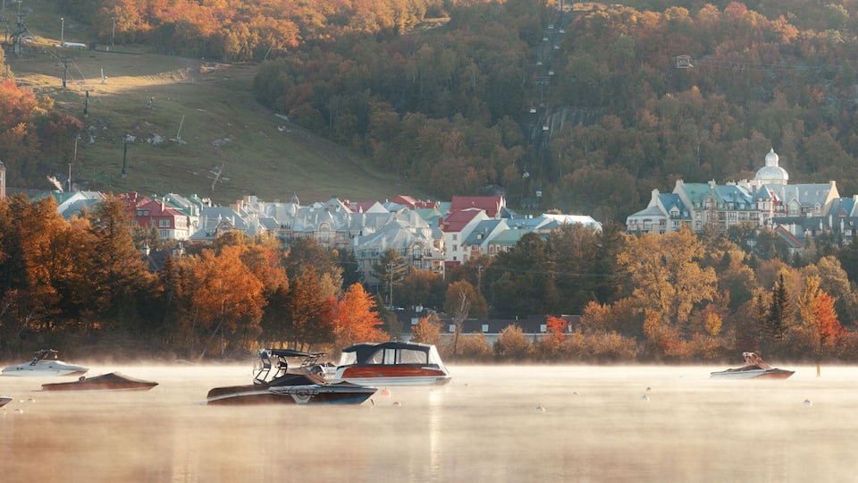 A lakeside town with autumn foliage, boats, and a hilltop church.