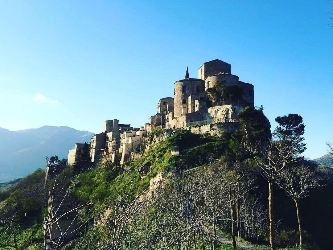 A medieval castle perched on a hill with a clear sky.