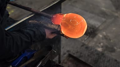 Spinning iron tube with which glass is blown, with a red-hot lump of liquid glass, one of which is formed a wine glass with a wad of wet newspaper in a glassworks in Kosta, Sweden