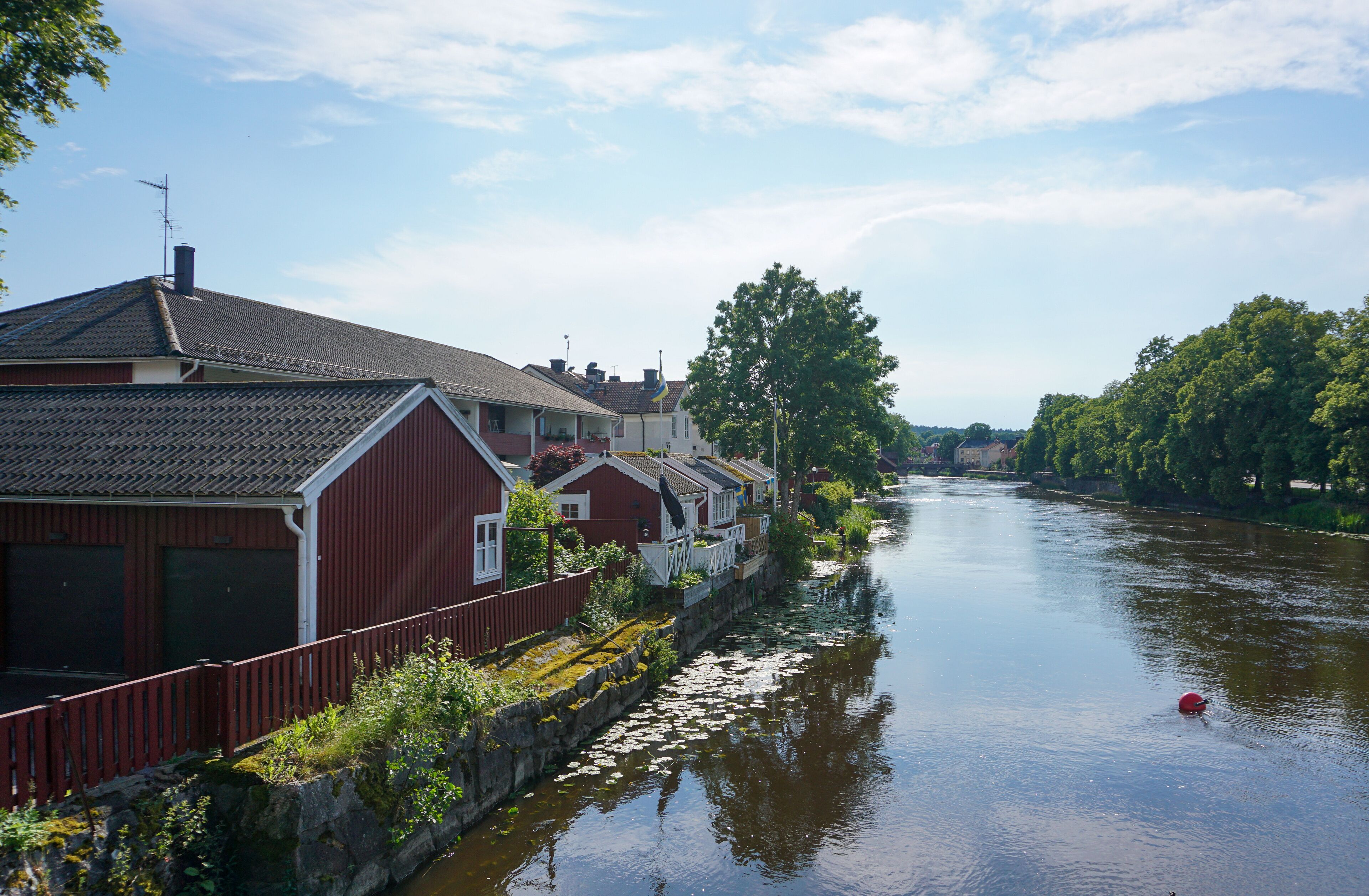 A calm river with houses on one side and trees on the other.