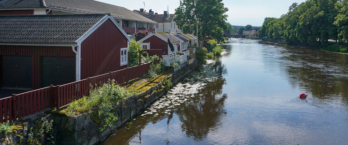 A calm river with houses on one side and trees on the other.