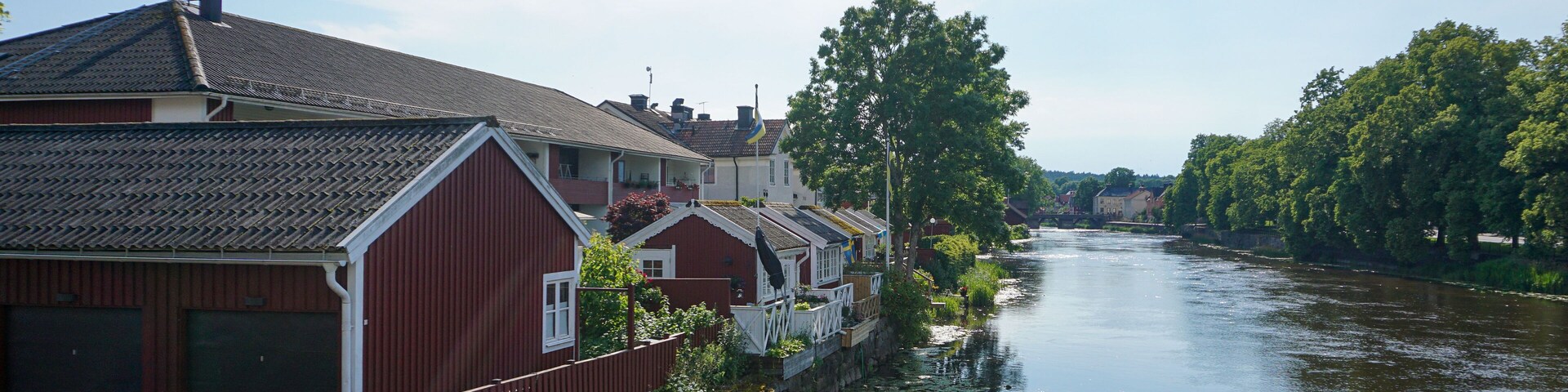 A calm river with houses on one side and trees on the other.