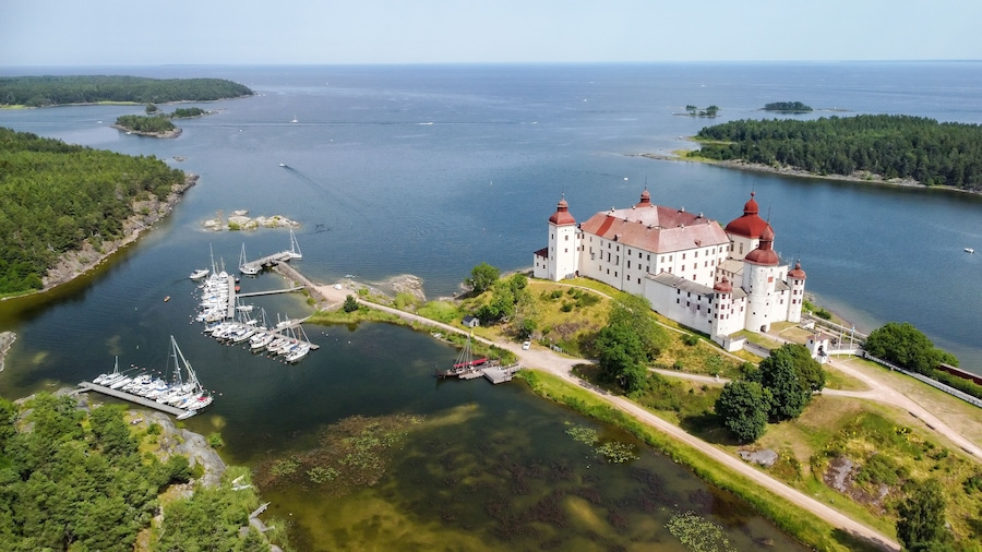 Un castillo junto a un lago con barcos y zona boscosa.