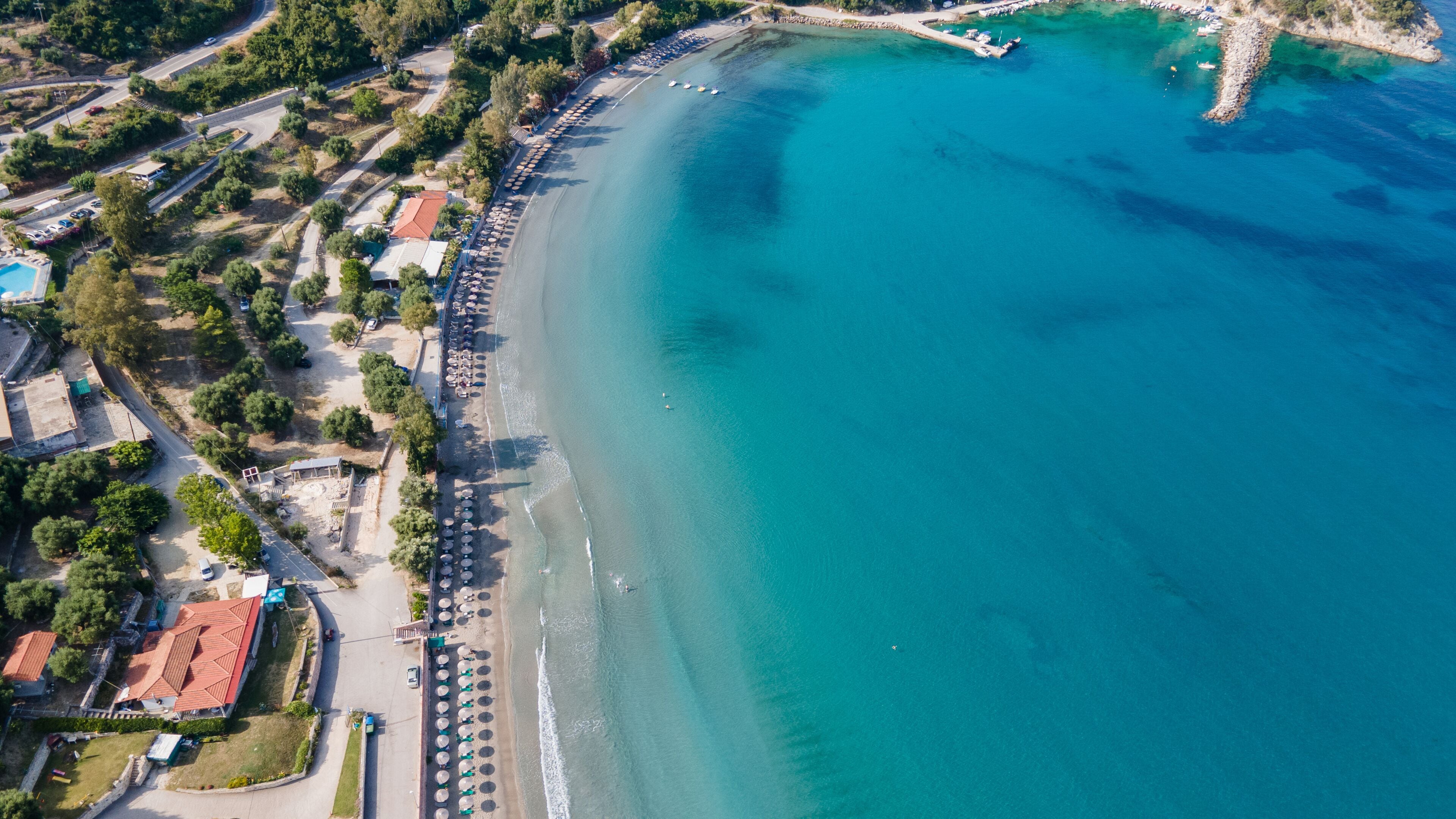 Bounty and pristine sandy shore with trees, Ionian Sea washes tropical coastline. Arillas Beach Syvota, Greece. Aerial view. View from above, aerial view of an emerald and transparent Mediterranean 
