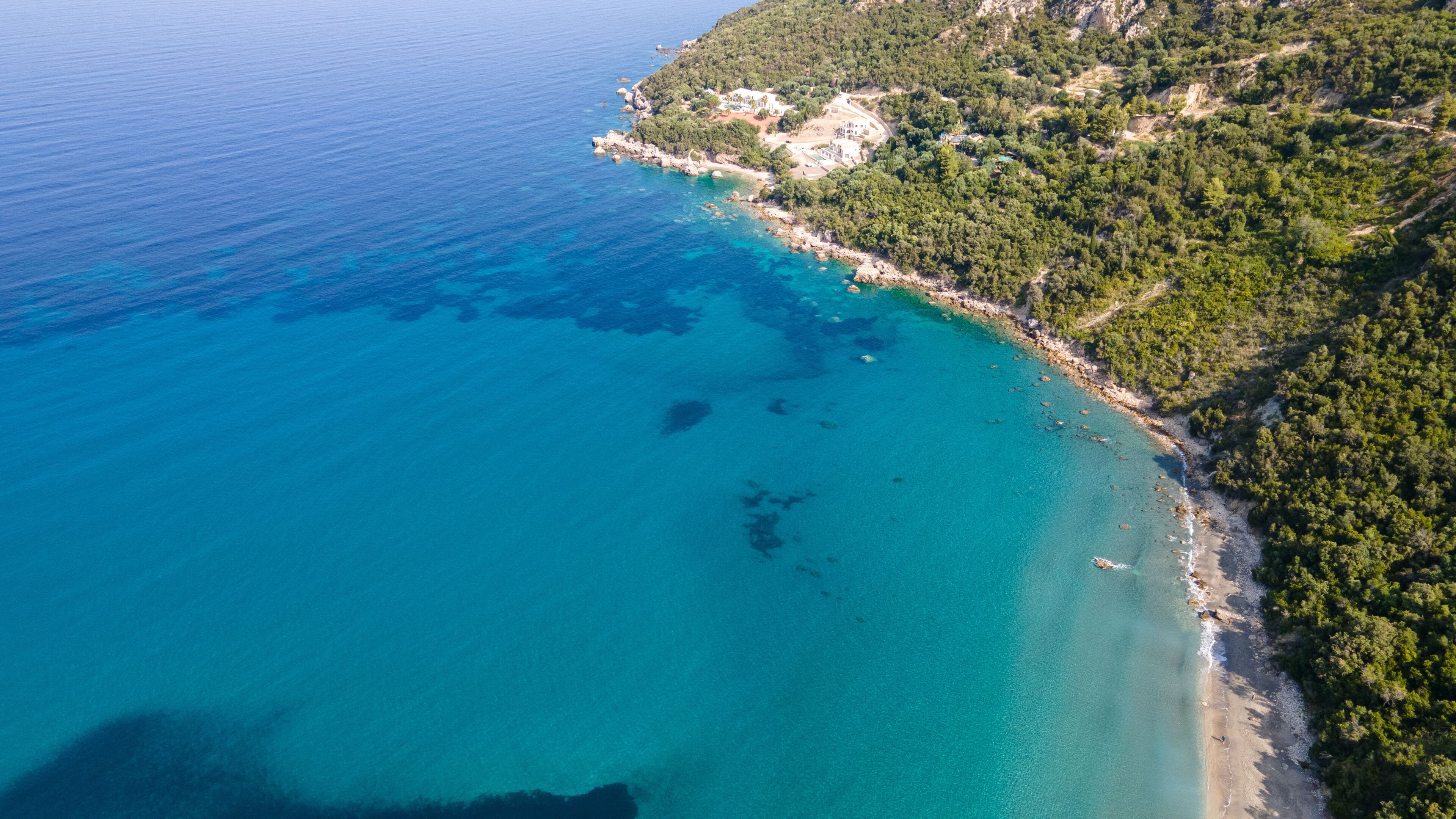 Bounty and pristine sandy shore with trees, Ionian Sea washes tropical coastline. Arillas Beach Syvota, Greece. Aerial view. View from above, aerial view of an emerald and transparent Mediterranean 