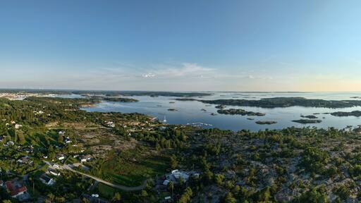 Panoramic Aerial View of Coastal Archipelago Near Strömstad, Sweden with Forested Terrain, Scattered Islands, and Sunlight Reflecting on Calm Sea