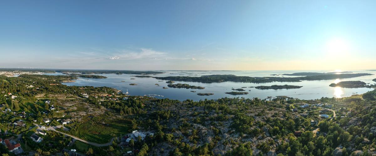 A coastal landscape with a large body of water, numerous small islands, and a town with houses and roads.