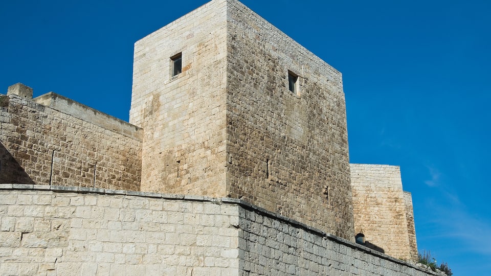 A historic stone wall with a tower and a smaller building.
