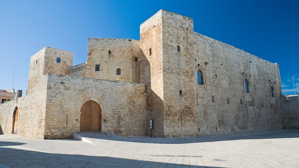 A historic stone building with arched doorways and a large wooden door.
