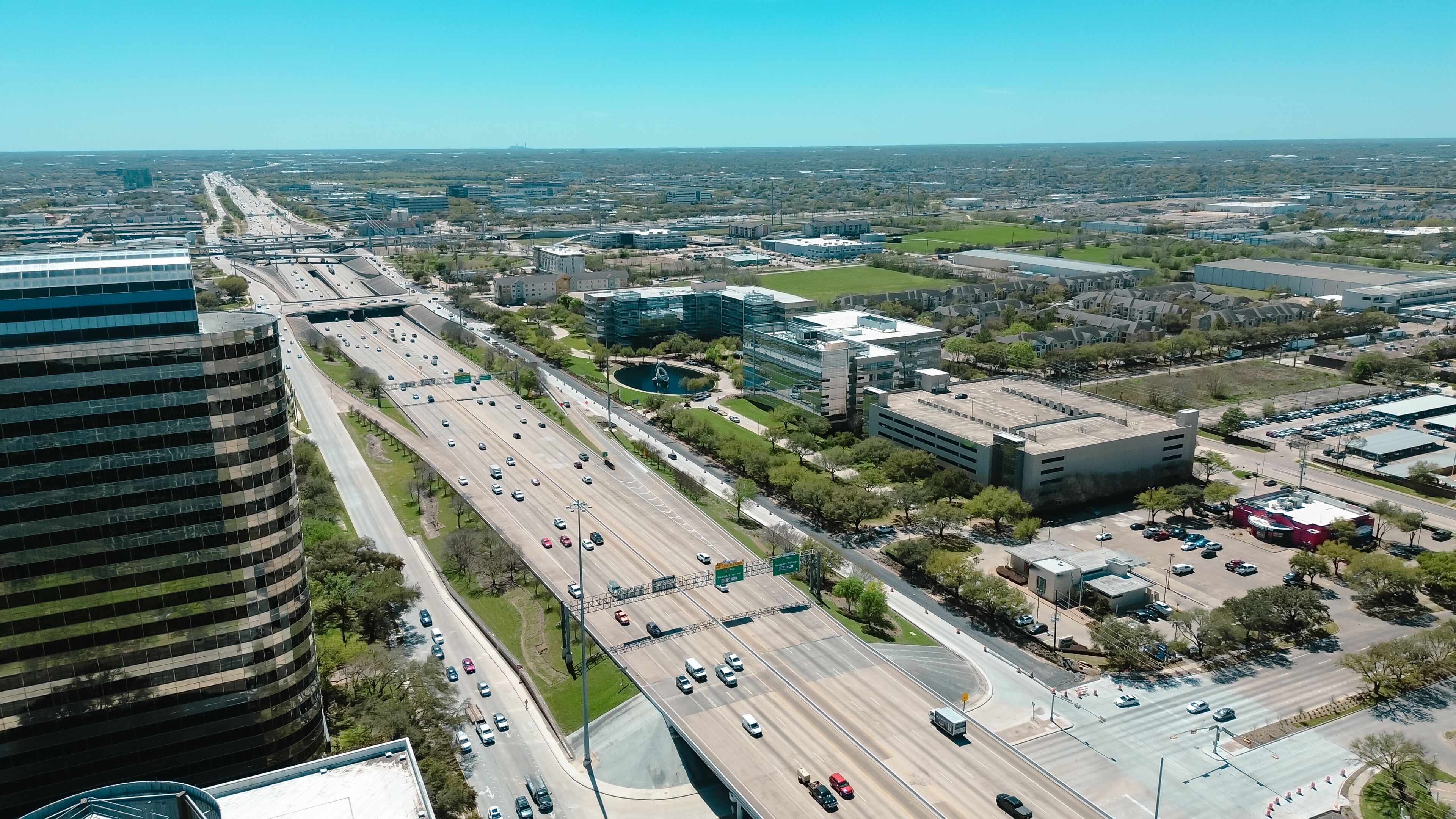 Modern glass office buildings, corporate office headquarters landmark in Westchase business district looking down busy Sam Houston Tollway and Richmond Avenue intersection, highway traffic aerial