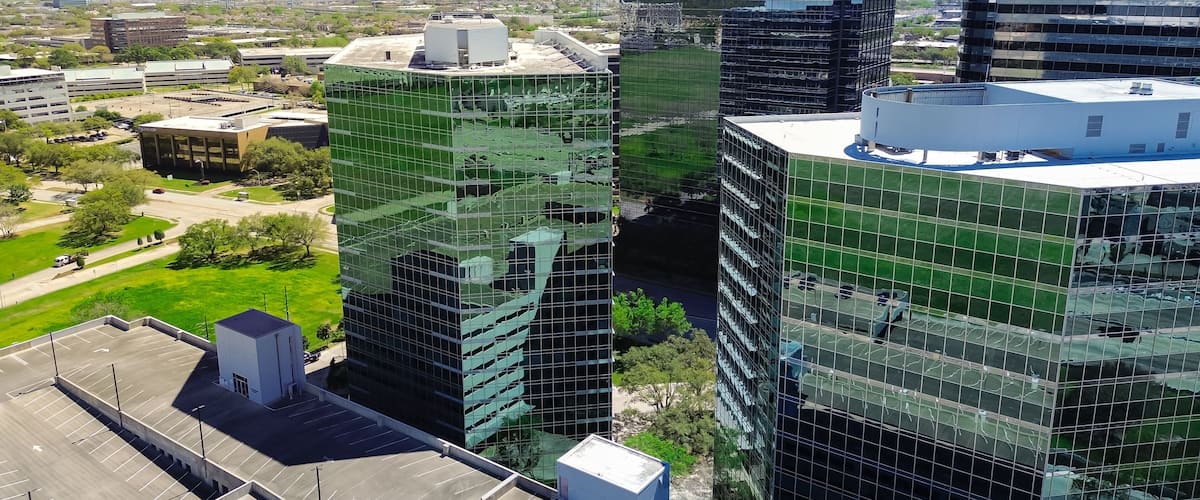 Glass office building with modern multistorey car park parking multilevel garage structure in busy Westchase business district, western Houston, Texas, rooftop structure space-efficient solution