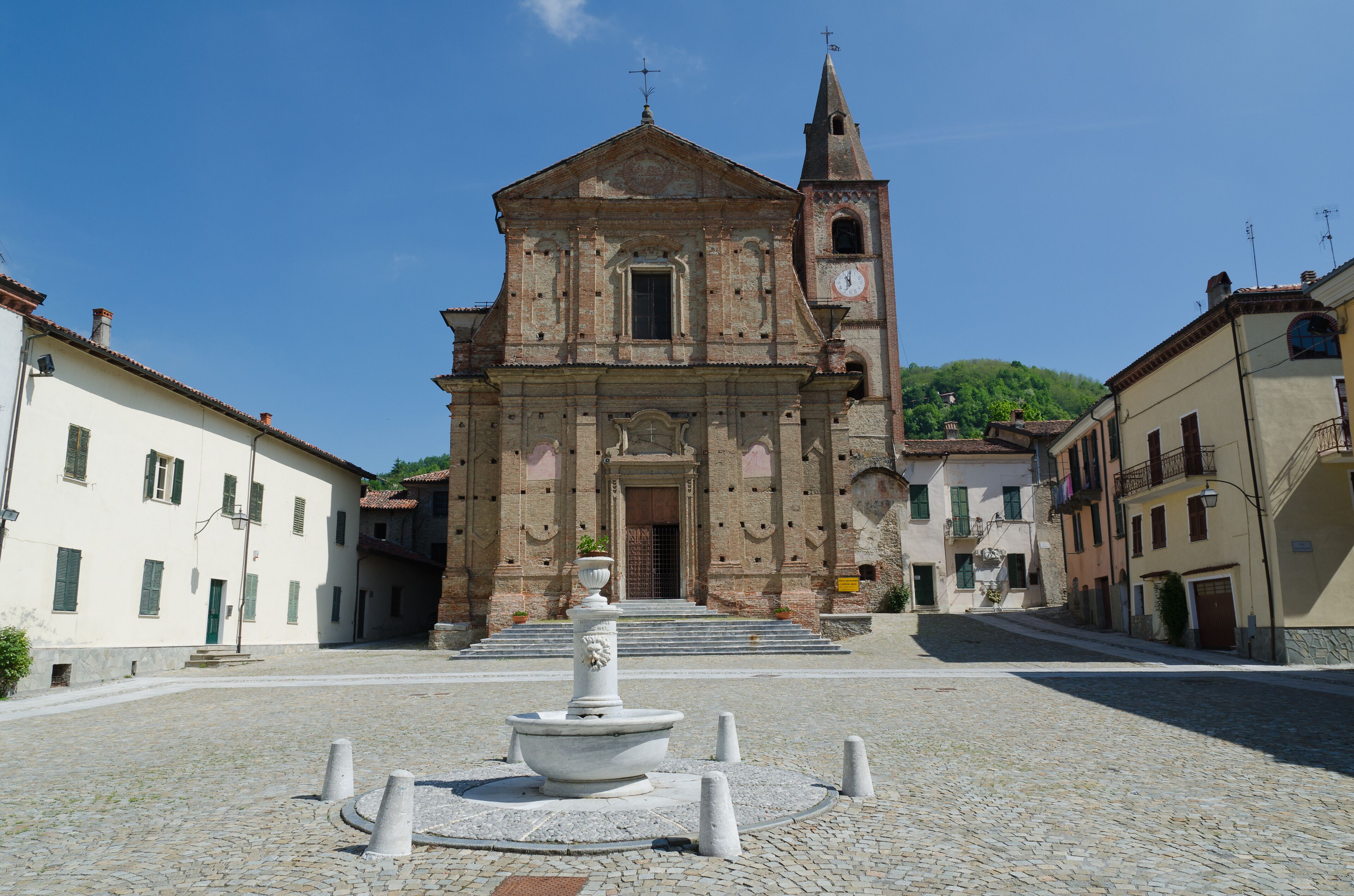A historic church with a bell tower and a fountain in the center of a cobblestone square.